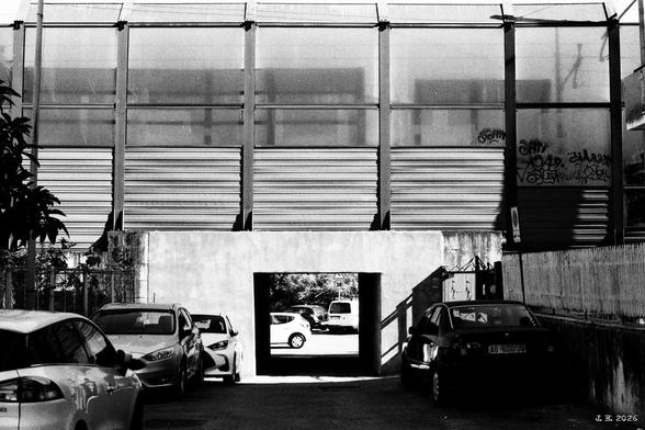 Sideways look at the train station in Prima Porta, Rome, Italy. The tracks are covered for noise protection. There is a square underpass underneath. Cars parked everywhere as usual. Leica R5 with 50 mm Summilux on Cinemot Fado film.